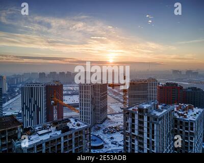 Immagine aerea di un grande cantiere che costruisce un nuovo quartiere residenziale. Bella alba invernale Foto Stock