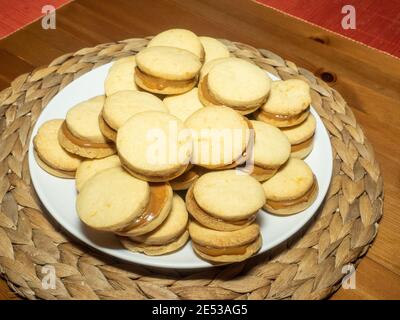 Gli alfajores tradizionali in Argentina, Perù e Uruguay consistono di due biscotti dolci rotondi fatti di farina di grano o amido di mais Uniti insieme con il dul Foto Stock