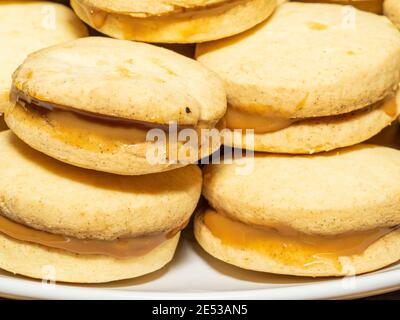 Gli alfajores tradizionali in Argentina, Perù e Uruguay consistono di due biscotti dolci rotondi fatti di farina di grano o amido di mais Uniti insieme con il dul Foto Stock