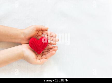 Mani che tengono il cuore rosso su sfondo bianco isolato, copy space, concetto di amore, speranza, assistenza sanitaria, donazione di organi, assicurazione e CSR, giornata del cuore mondiale, Foto Stock