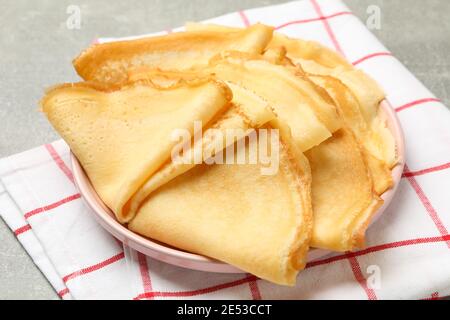 Asciugamano da cucina con piatto di frittelle sottili su tavolo grigio Foto Stock