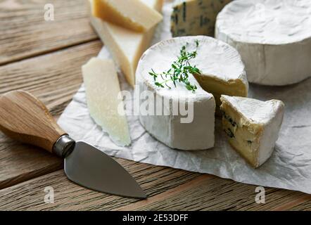 Vari tipi di formaggio, formaggio blu, bree, camambert su un tavolo di legno Foto Stock