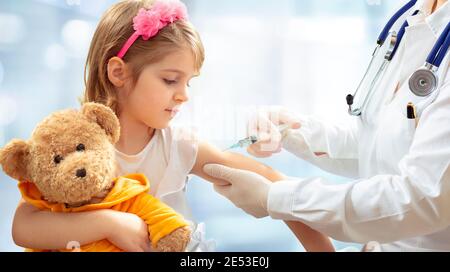 Concetto di vaccinazione - medico femminile vaccinare cute Little Girl on Sfondo blu Foto Stock