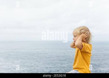 Ritratto del viso di capretto caucasico infastidito e infelice afferrò la testa e le orecchie chiuse. Concetto di bambino sconvolto o arrabbiato per le relazioni familiari, problemi sociali è Foto Stock