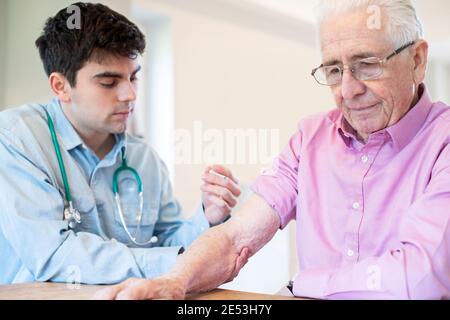 Maschio medico che dà l'iniezione di vaccino dell'uomo anziano in braccio con Siringa Foto Stock