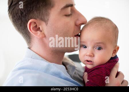 Primo piano di amorevole Padre coccolato e Kissing Baby Son A casa Foto Stock