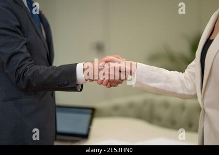 Stretta di mano femminile e maschile. Giovani freelance che lavorano insieme facendo stretta di mano durante la riunione d'affari in ufficio. Due giovani uomini d'affari in piedi Foto Stock