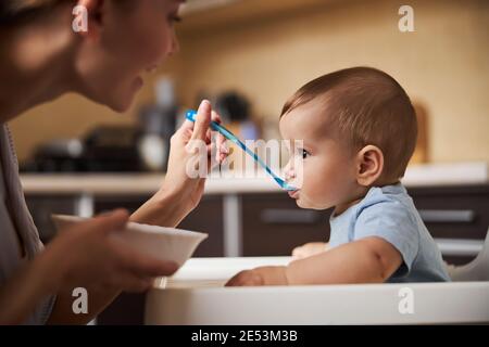 Foto messa a fuoco su tenero genitore che alimenta il suo bambino Foto Stock