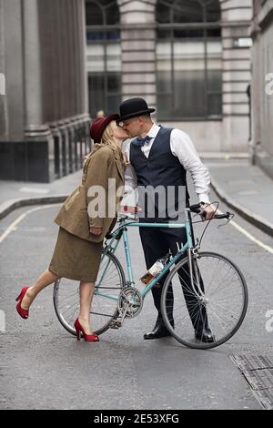 Uomo appassionato in bicicletta fermandosi e baciante donna in strada , Londra, Regno Unito Foto Stock