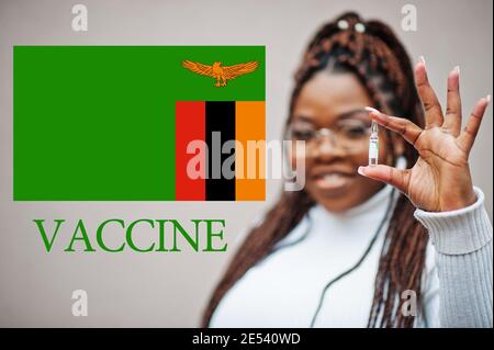 La donna africana mostra il vaccino per la Repubblica dello Zambia. Concetto di vaccinazione dei paesi africani. Foto Stock