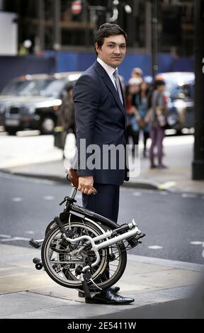 Uomo d'affari medio adulto che trasporta la bicicletta pieghevole - Executive con piegatura in bici Foto Stock