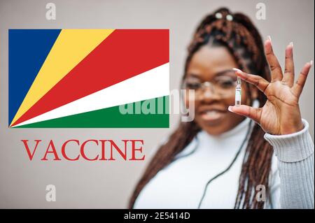 La donna africana mostra vaccino per la Repubblica delle Seychelles. Concetto di vaccinazione dei paesi africani. Foto Stock