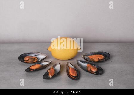 Frutti di mare al limone. Le deliziose cozze cucinate su fondo grigio. Minimalismo nella fotografia alimentare Foto Stock