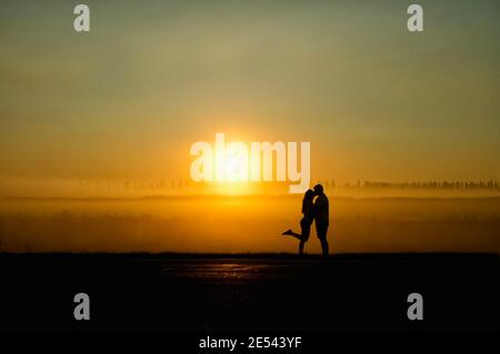 Una giovane coppia di amanti baciare al tramonto. Foto Stock