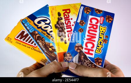 Primo piano di mani adulte che tengono una scatola di Nestle Buncha Crunch, Raisinets, Goobers, e latte tods. Foto Stock