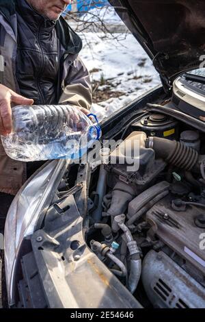 man versa l'antigelo nel serbatoio del liquido speciale Foto Stock