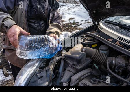 man versa l'antigelo nel serbatoio del liquido speciale Foto Stock