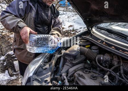 man versa l'antigelo nel serbatoio del liquido speciale Foto Stock