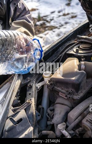 man versa l'antigelo nel serbatoio del liquido speciale Foto Stock