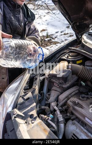 man versa l'antigelo nel serbatoio del liquido speciale Foto Stock