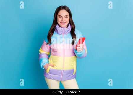 Ritratto fotografico di una donna sorridente che tiene il telefono in una mano isolato su sfondo color blu pastello Foto Stock