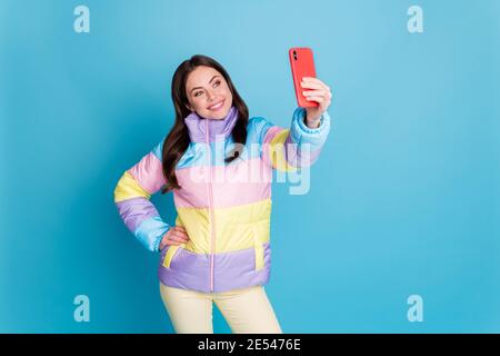 Ritratto fotografico di una donna sorridente che prende selfie tenendo il telefono in mano una mano isolata su sfondo color blu pastello Foto Stock