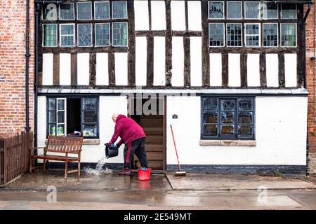 Bewdley, Worcestershire, Regno Unito. 26 gennaio 2021. Le acque alluvionali si defondono dopo che la città di Bewdley, Worcestershire, è stata parzialmente allagata dal fiume Severn. Un uomo si libera dall'acqua dal suo edificio secolare, che era sotto i cinque piedi di acqua alluvionata quando le difese del fiume fallirono. Credit: Peter Lopeman/Alamy Live News Foto Stock