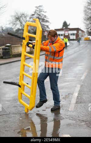 Bewdley, Worcestershire, Regno Unito. 26 gennaio 2021. Le acque alluvionali si defondono dopo che la città di Bewdley, Worcestershire, è stata parzialmente allagata dal fiume Severn. Un lavoratore abbatte le barriere di accesso alla sicurezza. Credit: Peter Lopeman/Alamy Live News Foto Stock