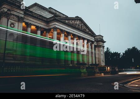 Lunga esposizione di un autobus verde che passa di fronte il museo dell'architettura nella città di cambridge Foto Stock