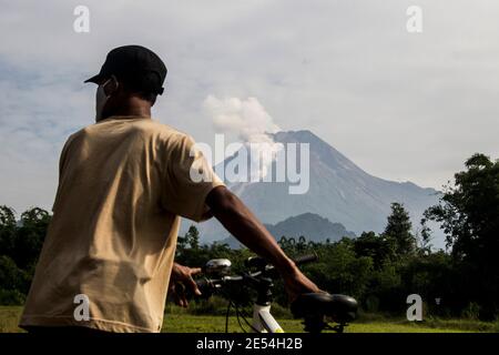 Sleman, YOGYAKARTA, INDONESIA. 26 gennaio 2021. I ciclisti vedono il Monte Merapi, il vulcano più attivo dell'Indonesia, che spara nuvole calde a 1,000 metri a sud-ovest, a monte del fiume Krasak e del fiume Boyong, Pakem, Sleman, Yogyakarta, martedì 26 gennaio 2021. Il Monte Merapi è una delle montagne più volatili tra gli oltre 120 vulcani del paese. Credit: Slamet Riyadi/ZUMA Wire/Alamy Live News Foto Stock