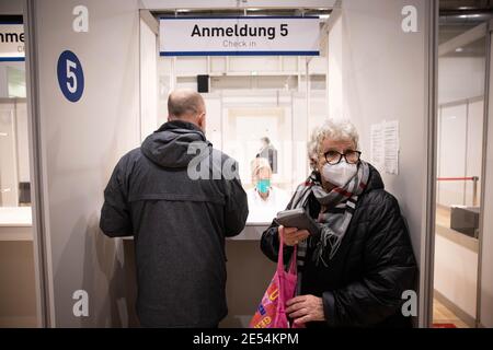 Amburgo, Germania. 26 gennaio 2021. Accompagnato dal figlio, Brigitta Kledke (r), di 83 anni, si registra per la seconda vaccinazione Corona presso il centro di vaccinazione di Amburgo. Tre settimane dopo la messa in funzione del centro di vaccinazione di Amburgo nelle sale espositive, le prime seconde vaccinazioni sono state somministrate lì martedì. Dal 5 gennaio, le persone con più di 80 anni e i dipendenti dei servizi di assistenza sono chiamati a vaccinarsi presso il centro. Credit: Christian Charisius/dpa/Alamy Live News Foto Stock