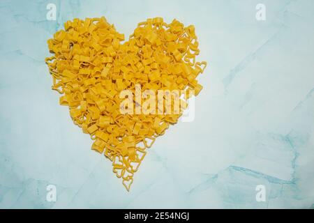 Cibo di fondo e concetto valentino. Pasta a forma di cuore su fondo di marmo blu. Concetto di amanti della pasta. Foto di alta qualità Foto Stock