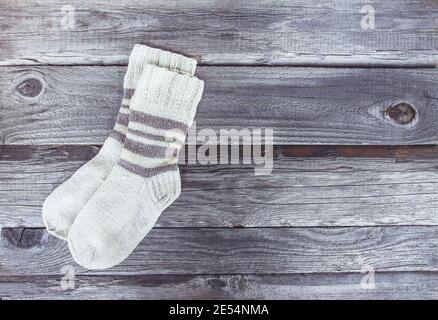 Calze a maglia calda fatte a mano di filato di lana su fondo ruvido di legno. Foto Stock