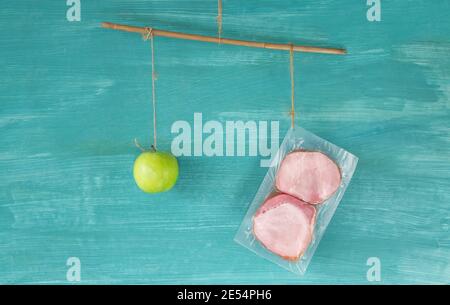 Alimentazione sana e concetto di dieta a basso contenuto di carboidrati, scala con mela e di scarsa qualità, carne a buon mercato, concetto, spazio di copia Foto Stock