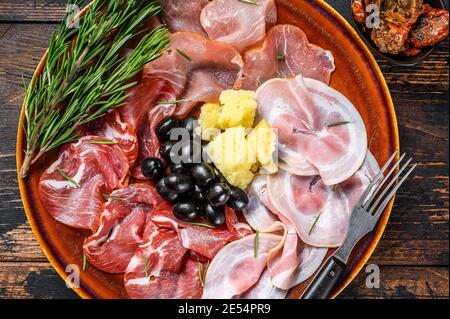 Piatto di carne italiana con prosciutto, bresaola, pancetta, salame e parmigiano. Sfondo di legno scuro. Vista dall'alto Foto Stock