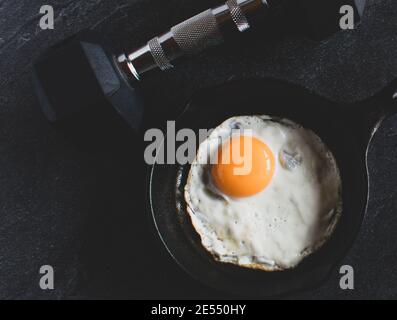 manubri con uova fritte in padella al buio bakground dall'alto Foto Stock