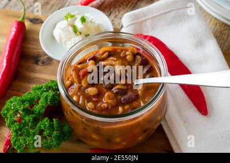 zuppa di fagioli misti appena cotti con carne di pollo servita in recipiente di vetro su tavolo di legno Foto Stock