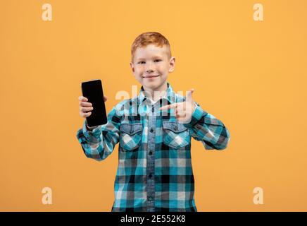 Ragazzo sorridente che punta al telefono cellulare con schermo vuoto Foto Stock