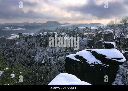 Lohmen, Germania. 25 Gennaio 2021. Rocce innevate nelle montagne di arenaria dell'Elba con vista sul Ponte di Bastei. Credit: Tino Plunert/dpa-Zentralbild/ZB/dpa/Alamy Live News Foto Stock