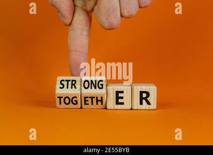 Simbolo di Unione più forte. L'uomo d'affari trasforma i cubi e trasforma la parola insieme in più forte. Splendido sfondo arancione, spazio per la copia. Business, motiva Foto Stock