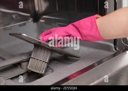 Donne in guanti di gomma che mostrano un filtro per lavastoviglie sporco. Preparazione per la pulizia. Pulizia a molla. Foto Stock