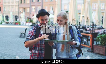 Zoom di turisti che tengono la mappa e sorridono alla fotocamera. Si trova su una grande piazza del mercato della vecchia città europea. Foto Stock