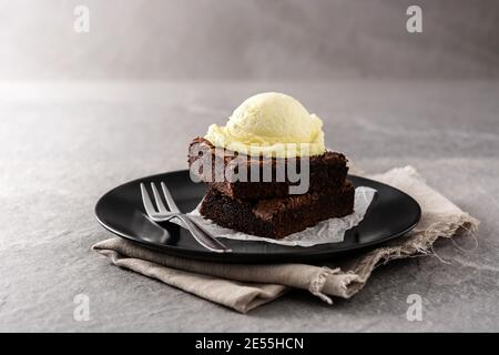 Brownie con cucchiaio di gelato alla vaniglia su pietra grigia Foto Stock