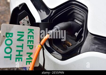 Cavo di ricarica per auto elettrico collegato all'auto con una nota per dire tenere il cavo nel bagagliaio, Regno Unito Foto Stock
