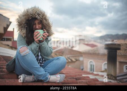 Donna in un momento di relax bere tè sul tetto la sua casa Foto Stock