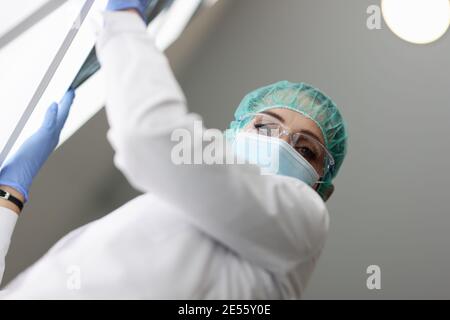 Medic sta tenendo una radiografia nella maschera medica protettiva Foto Stock