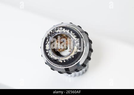 Primo piano dell'aeratore del rubinetto vecchio su sfondo bianco. Miscelatore lavello rotto Foto Stock