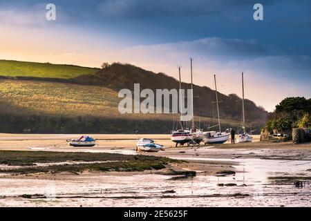 La luce serale sulle barche ormeggiate e ormeggiate sul litorale del fiume Gannel a bassa marea a Newquay in Cornovaglia. Foto Stock