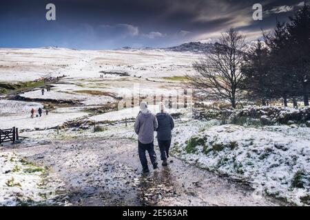 Le persone che si divertiscono a camminare nella neve sul selvaggio e aspro Rough Tor su Bodmin Moor in Cornovaglia. Foto Stock
