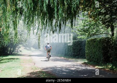 Un ciclista maschile in bicicletta lungo il sentiero accanto al Tamigi. Foto Stock